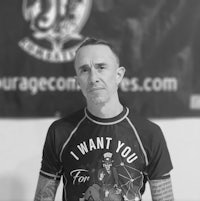 a man with tattoos standing in front of a wall